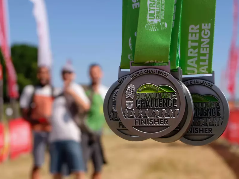 a close up of four silver and green finisher medals for the Cotswold Way Ultra Challenge