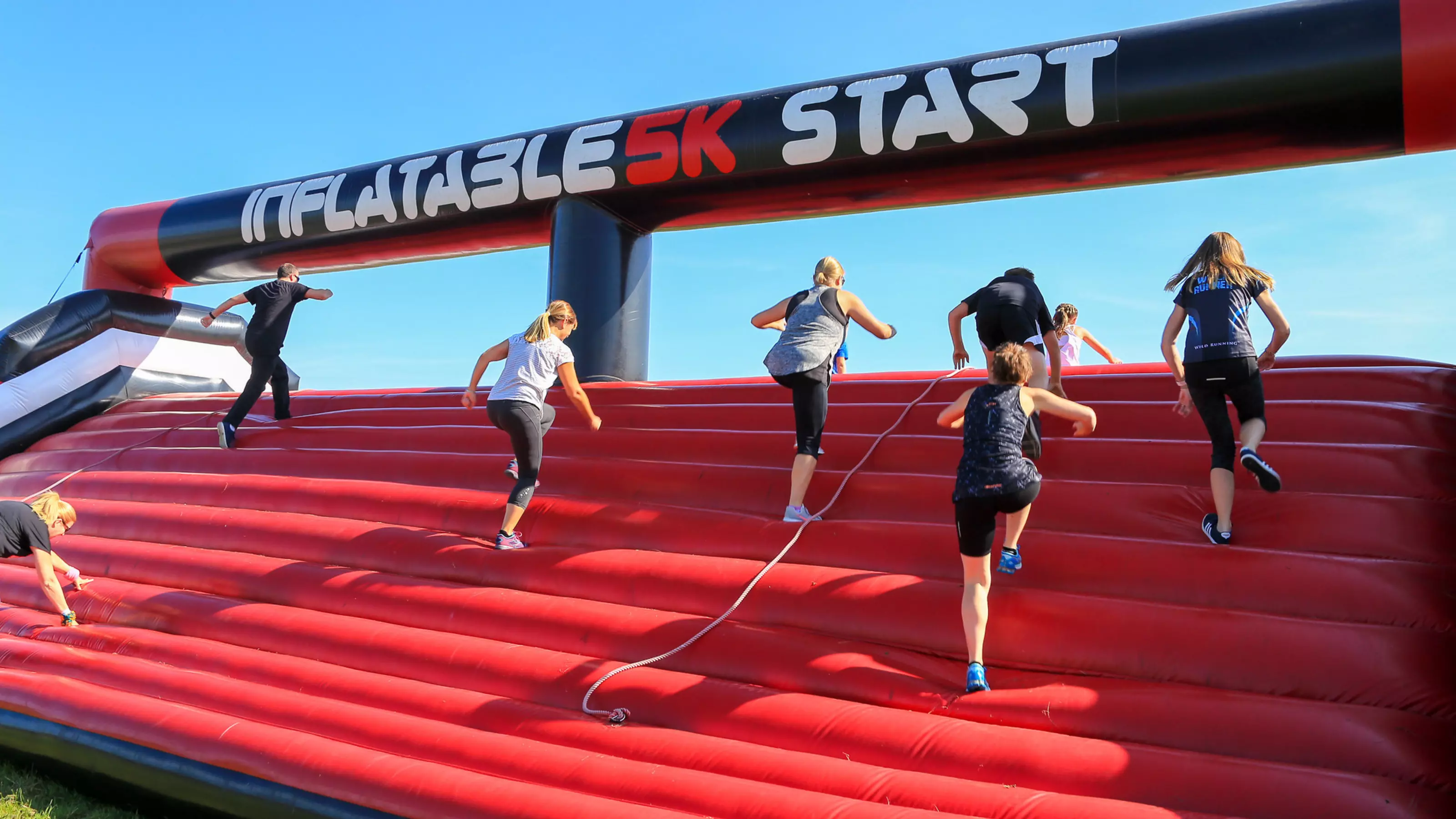 Inflatable 5k participants climb over an inflatable obstacle.