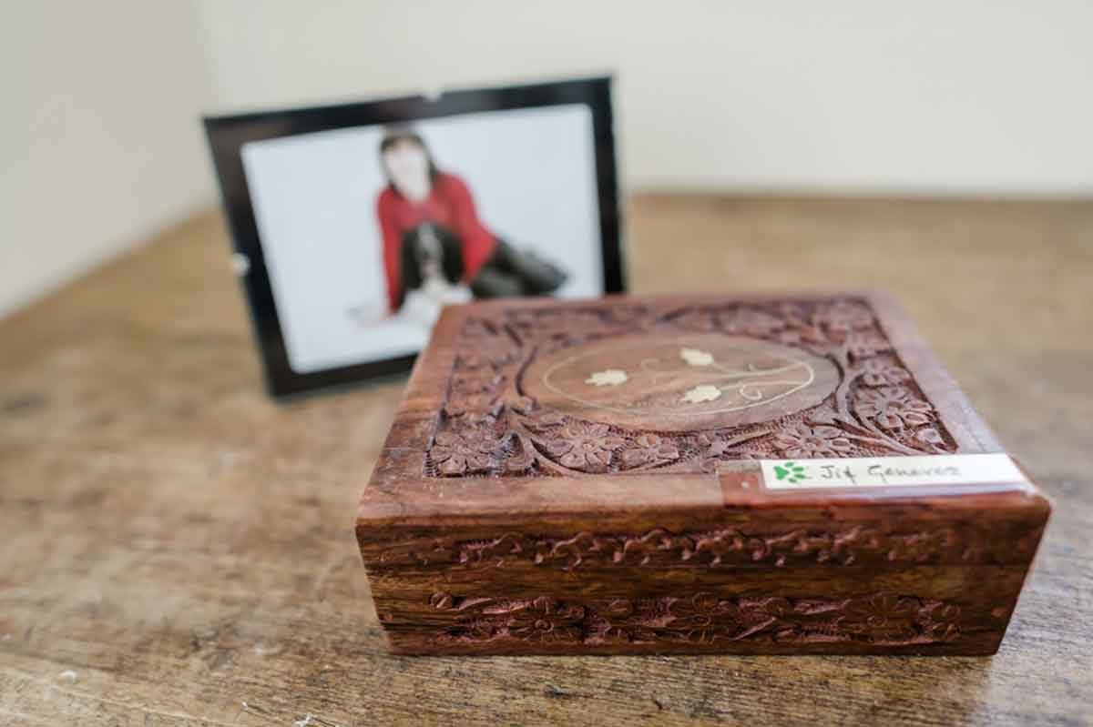 Box containing pet ashes with photo of pet and owner blurred in background