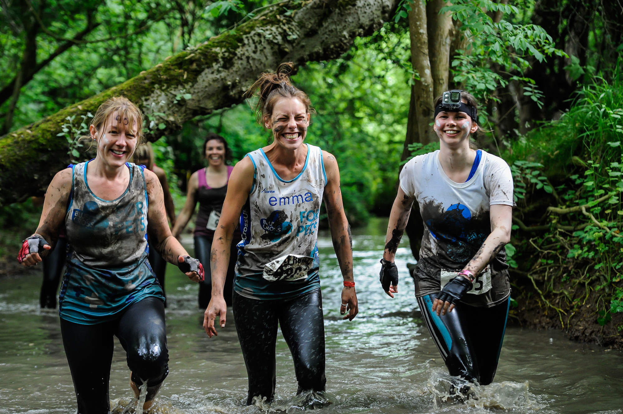 Three women running through river