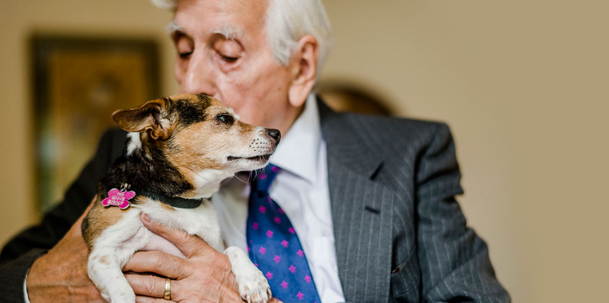 Older gentleman with jack russell in arms giving him a kiss