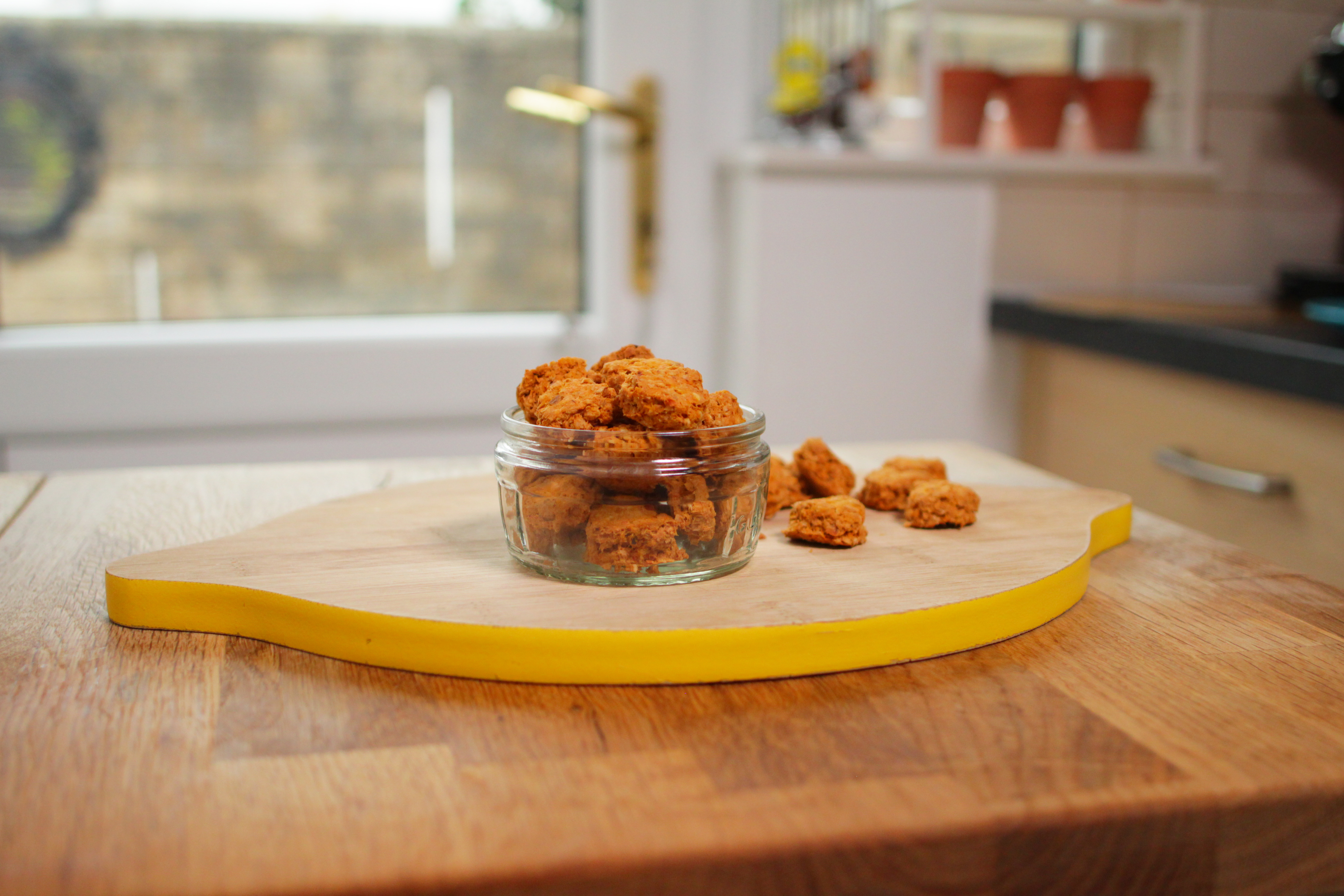 Bite-sized biscuits in a glass ramekin on a chopping board 