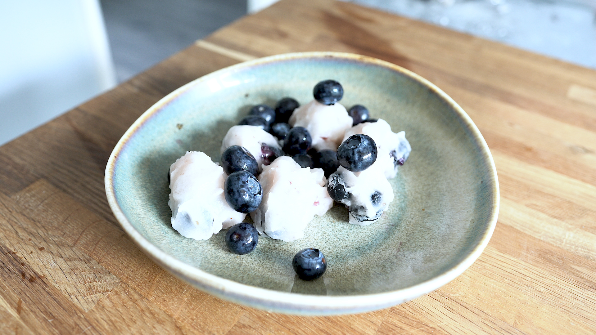 Frozen coconut and blueberry treats on mint green plate