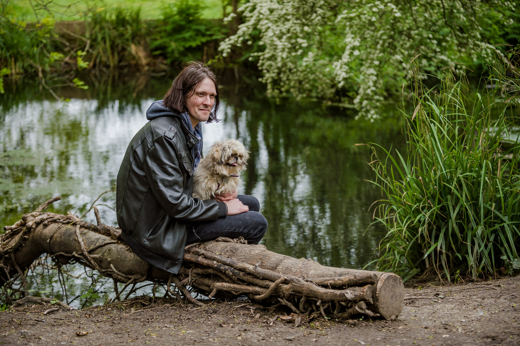 James and Chewbie sitting together on a log beside a river