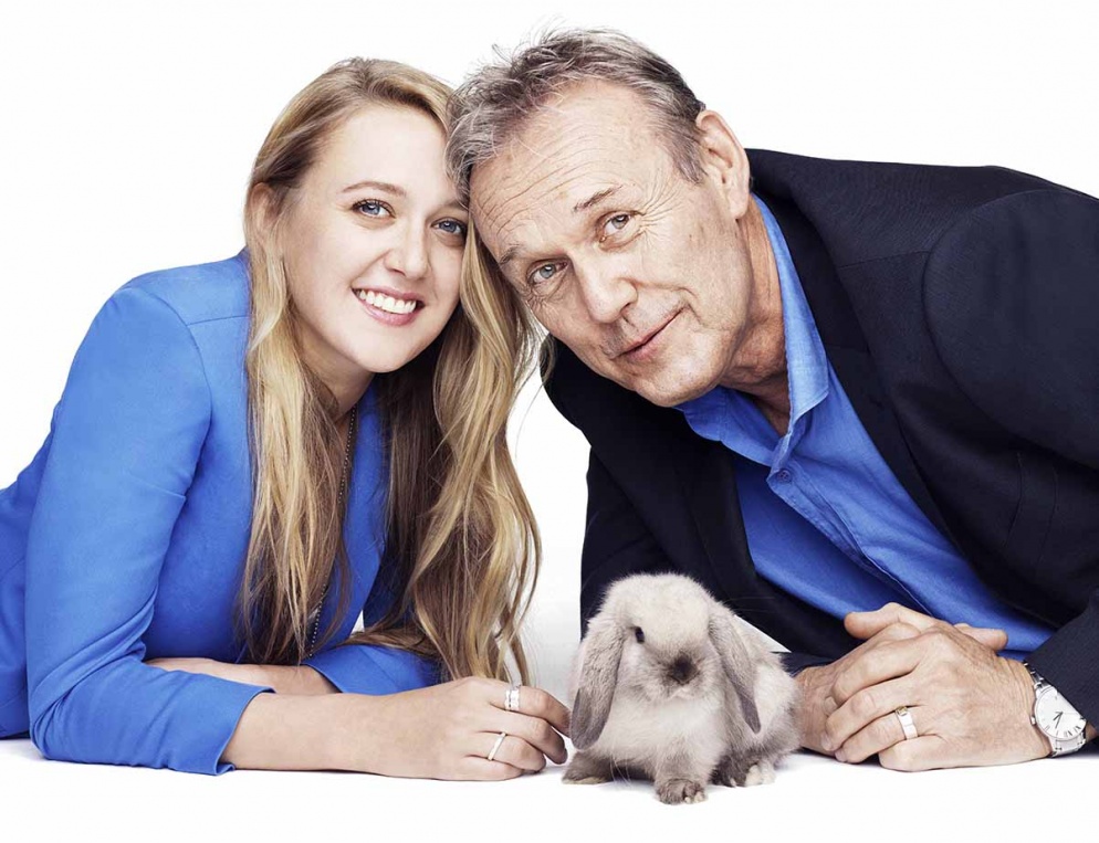 Actress Emily Head in blue top looking to camera, little lop eared grey rabbit in the middle and Anthony Head on the right with in blue shirt with blazer over it