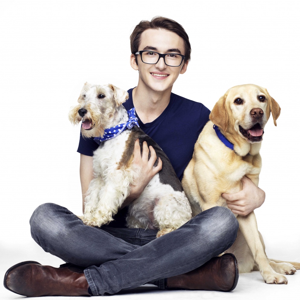 Issac Hempstead Wright sat with two dogs on his lap, smiling to camera
