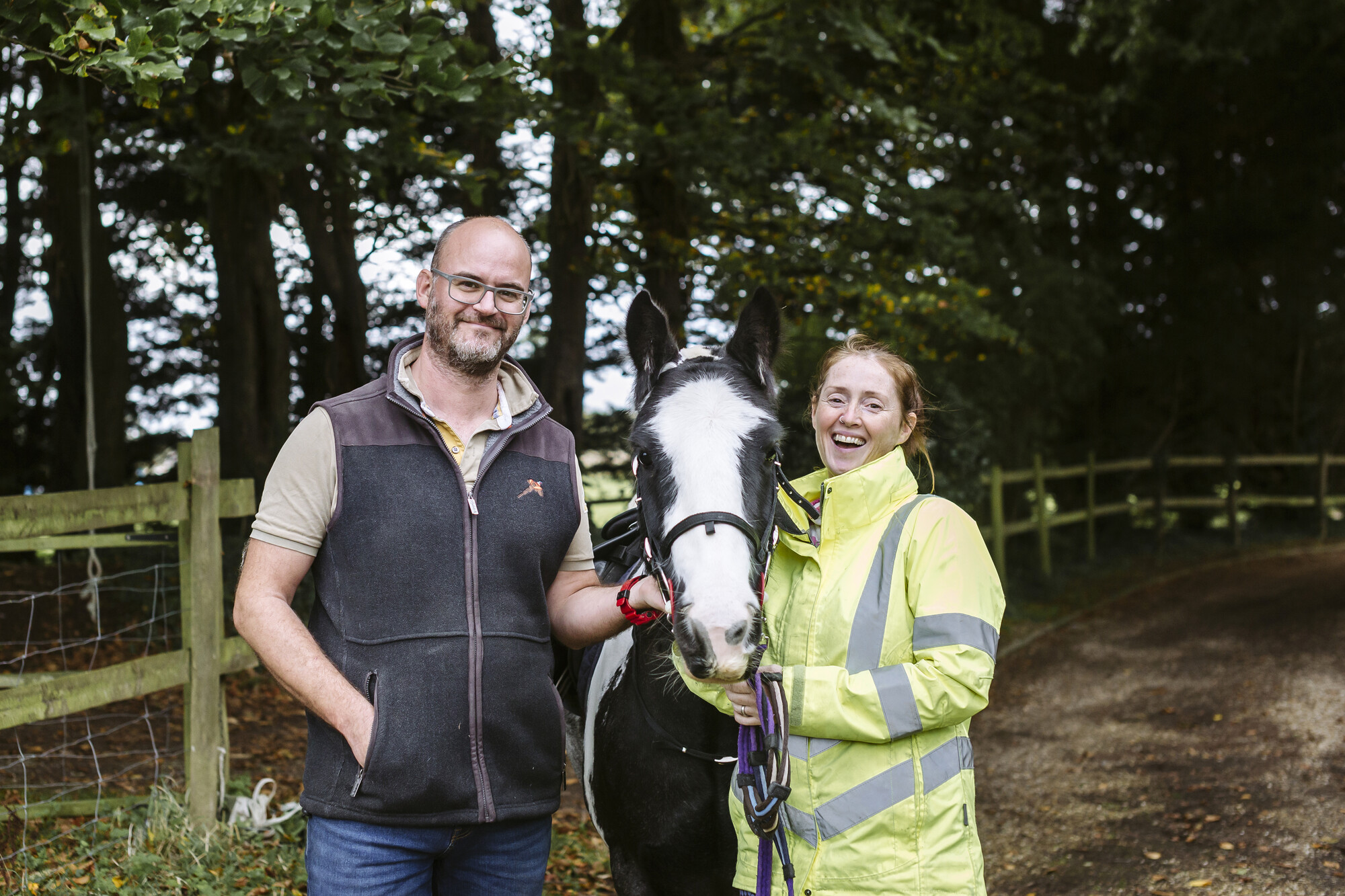 Micky, the black and white horse, with new owners Abi and James standing either side of him