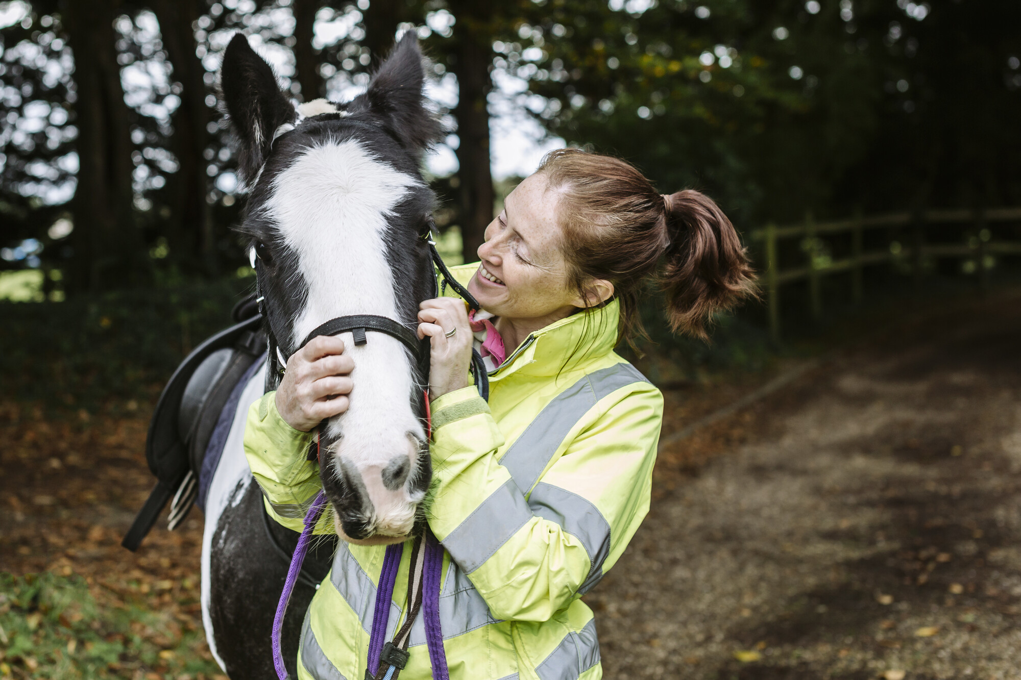 Abi with her arms around black and white horse Micky, looking at him smiling