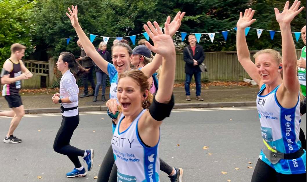 Three female runners running along a road, with blue and white Blue Cross running t-shirts