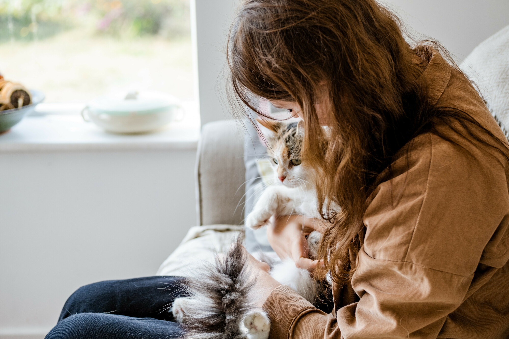 Lisa snuggles up with her beloved cat, Elya, on the sofa as they are reunited for the first time in four months