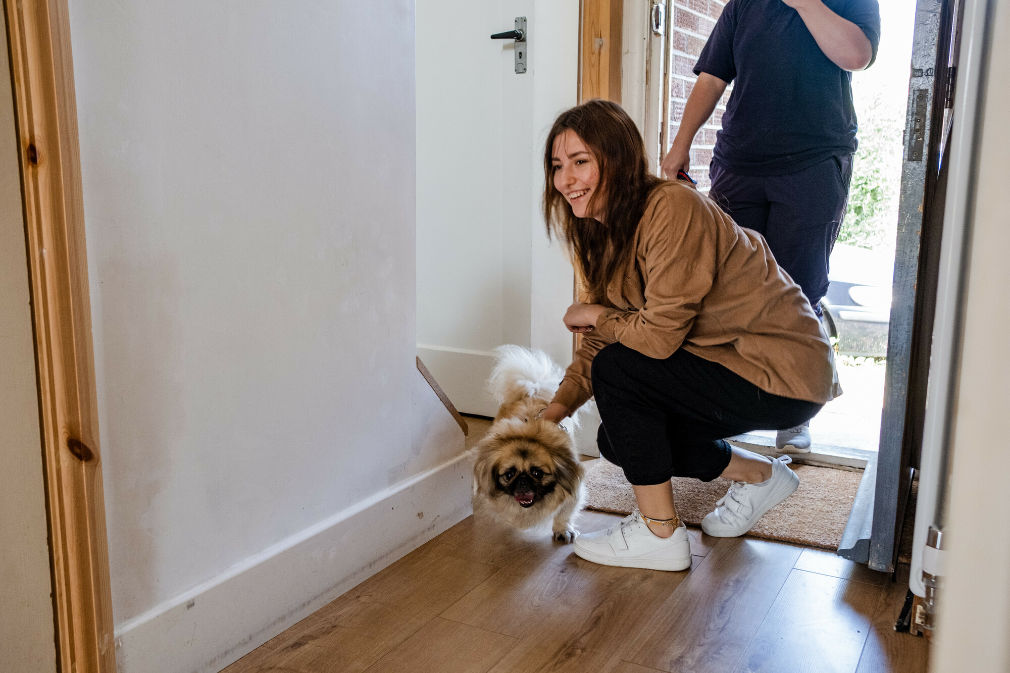Lisa brings dog Bonya through the door of the home they have found refuge in. Lisa is smiling widely.