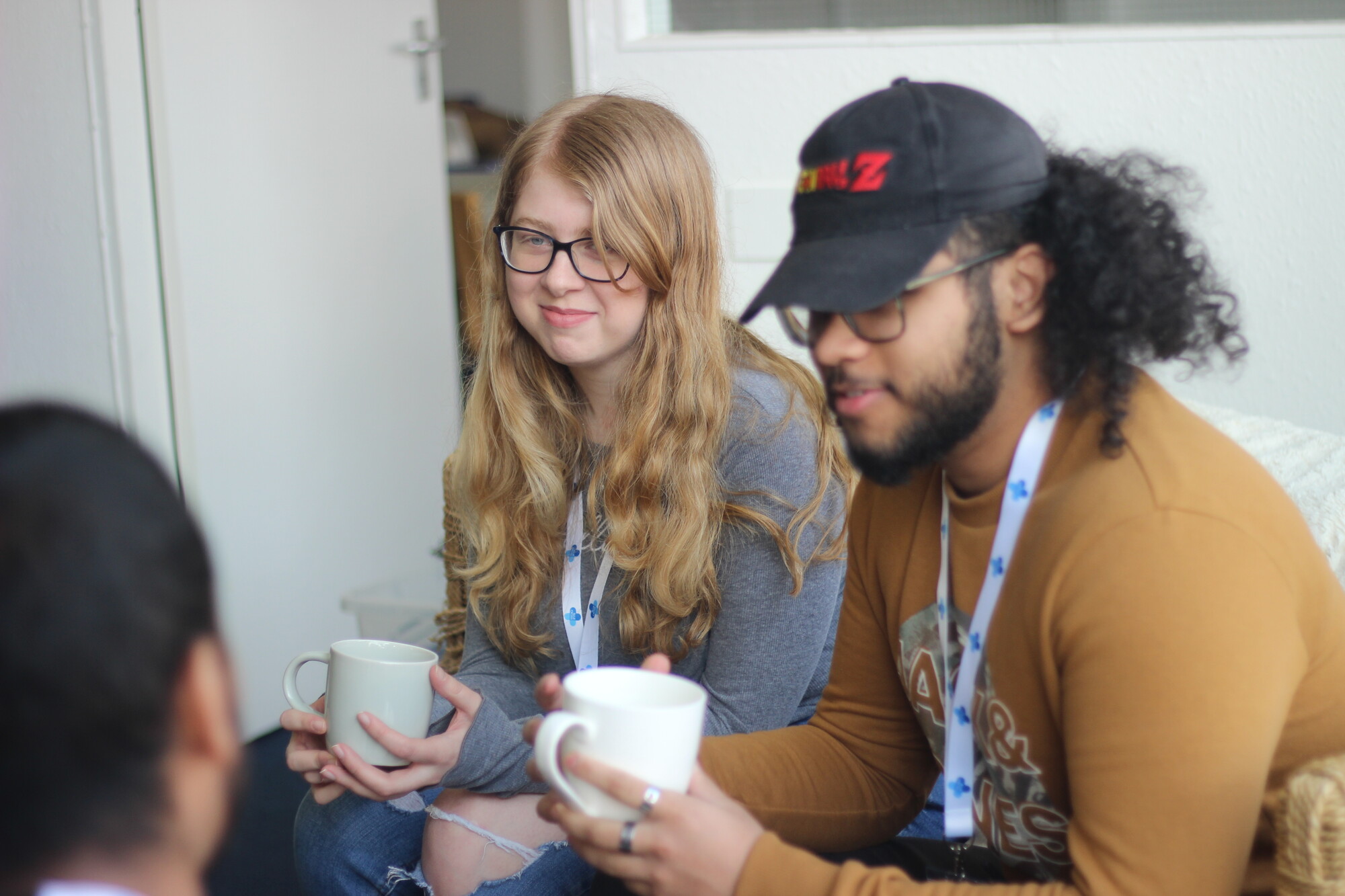 A young woman and young man sitting next to each other chatting over a cup of tea