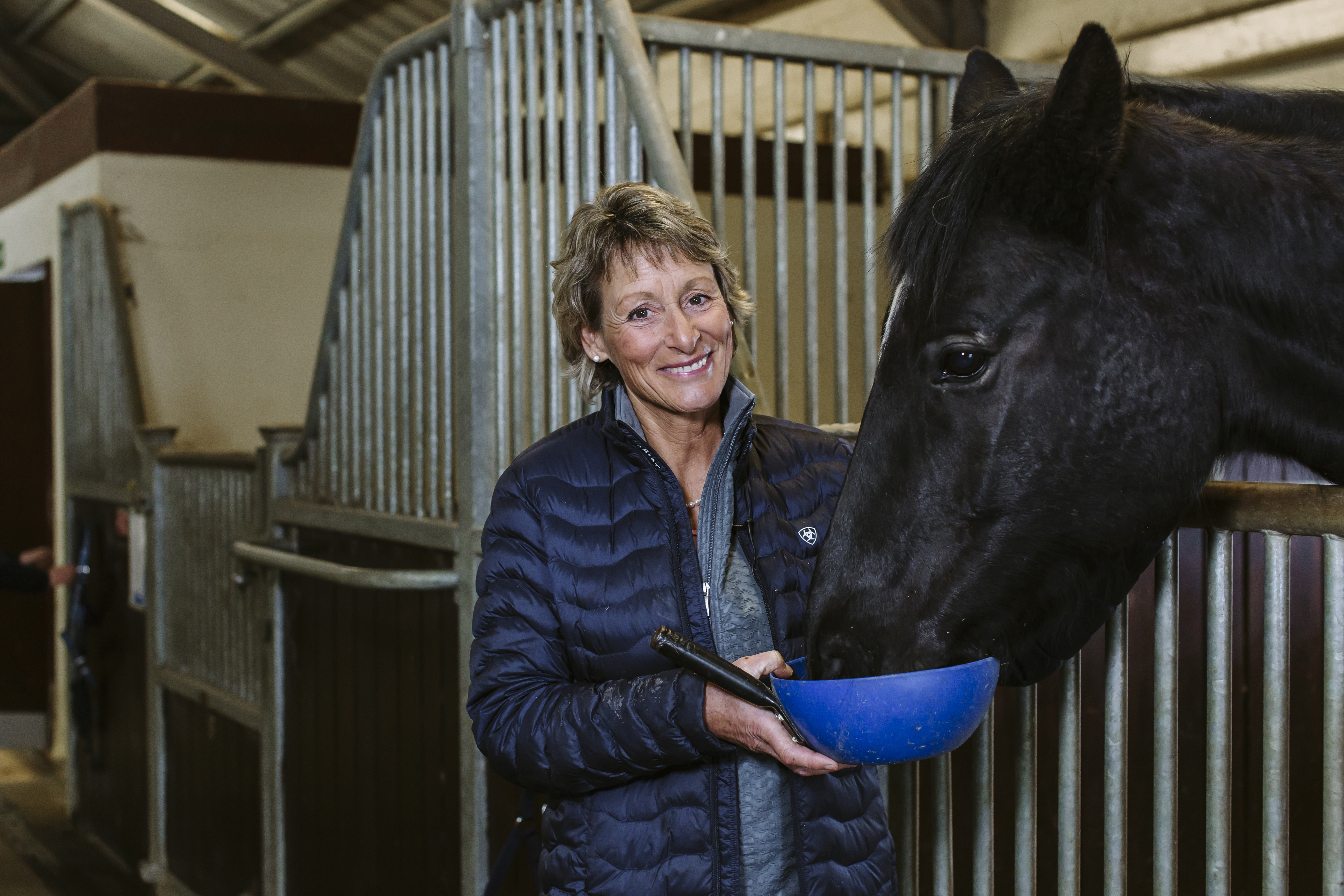 Mary King feeds a horse from a feeding bowl.