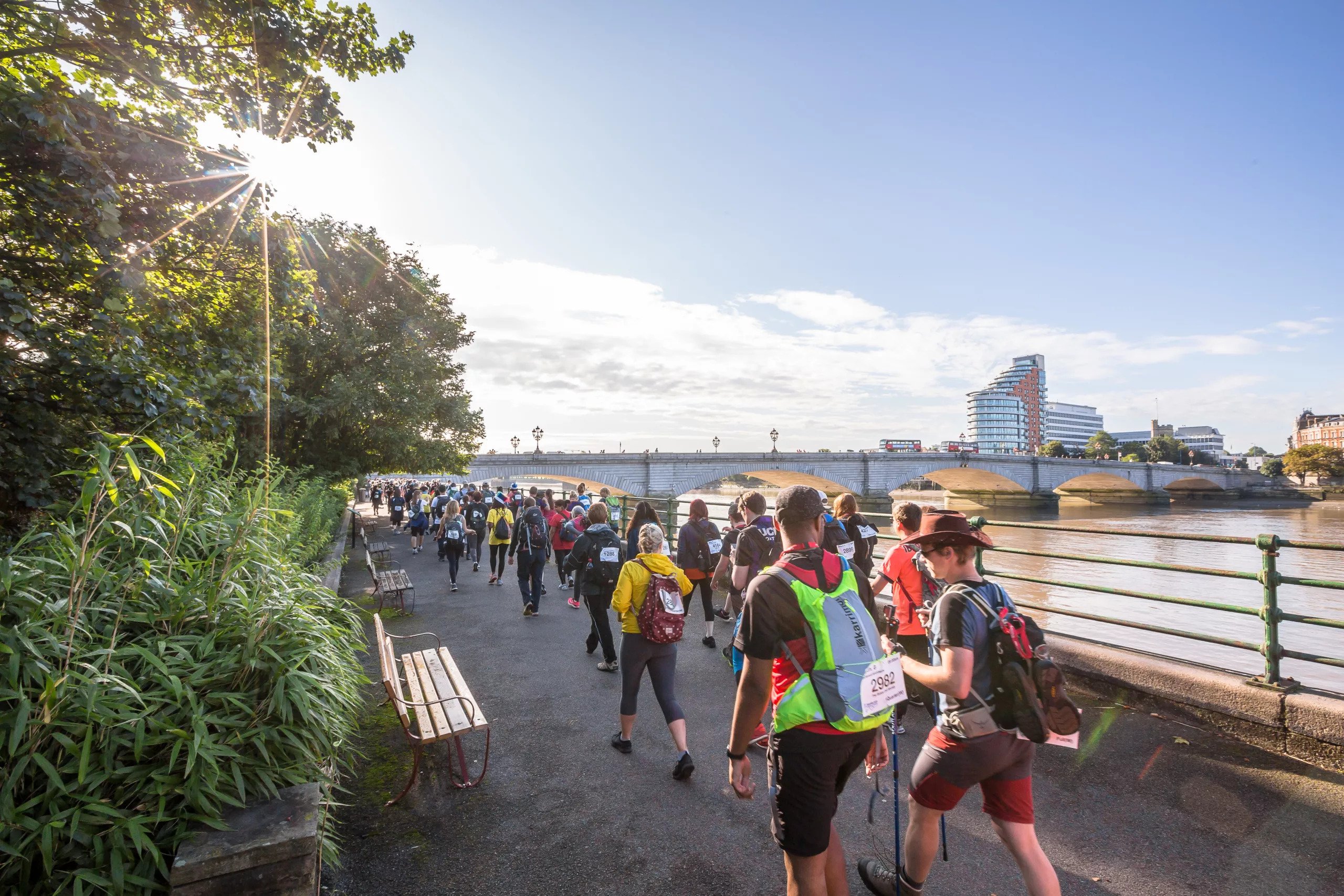 Attendees of the Thames Bridge Trek walk by the Thames river.