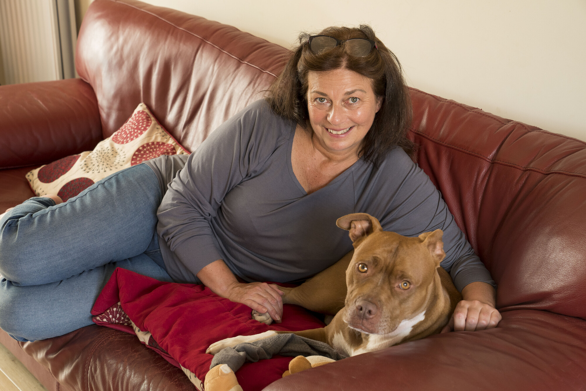 Anita and Lola cuddled up on a red leather sofa