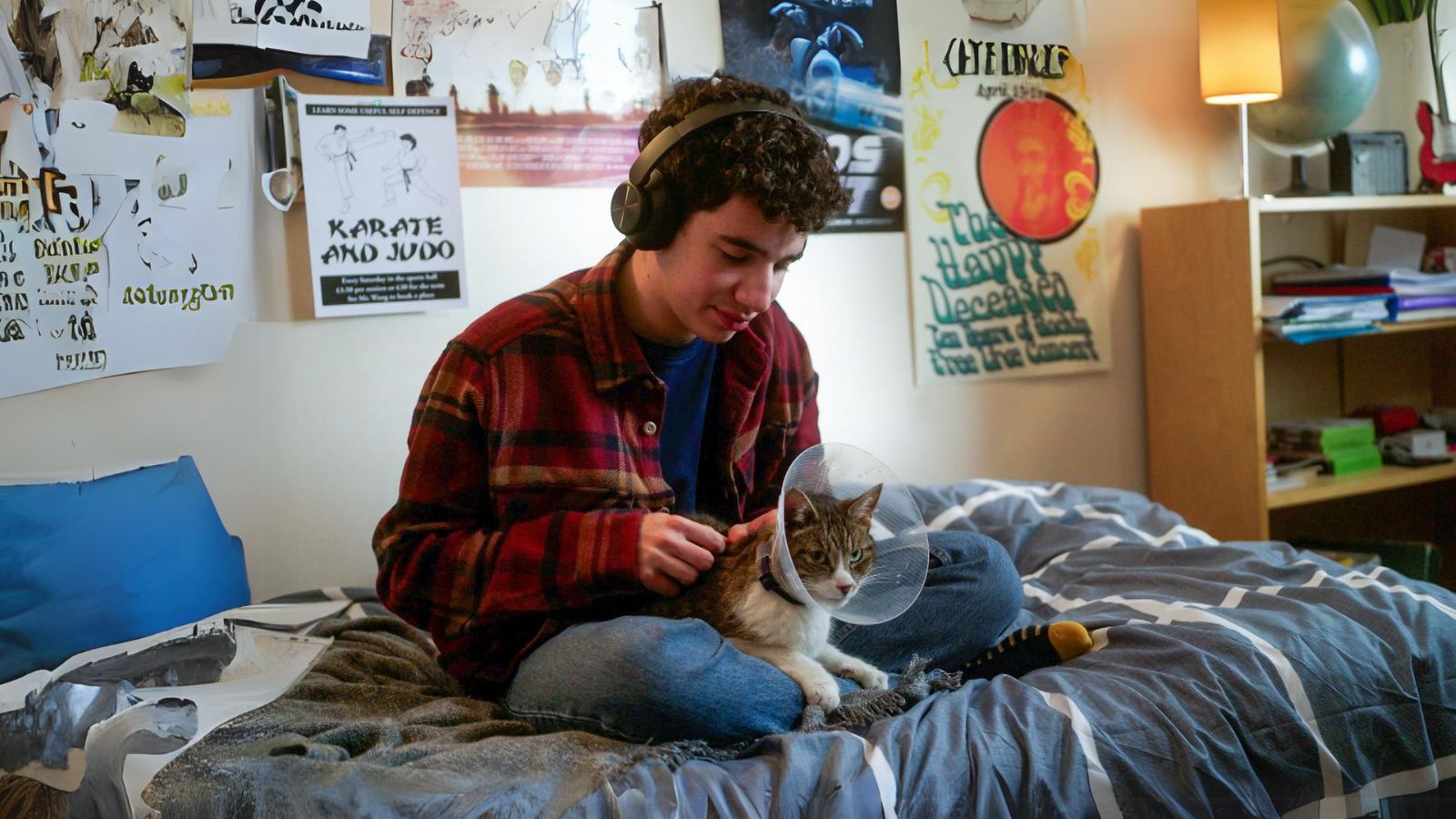 Teenage boy sitting on his bed and his cat, Thor, sitting in his lap