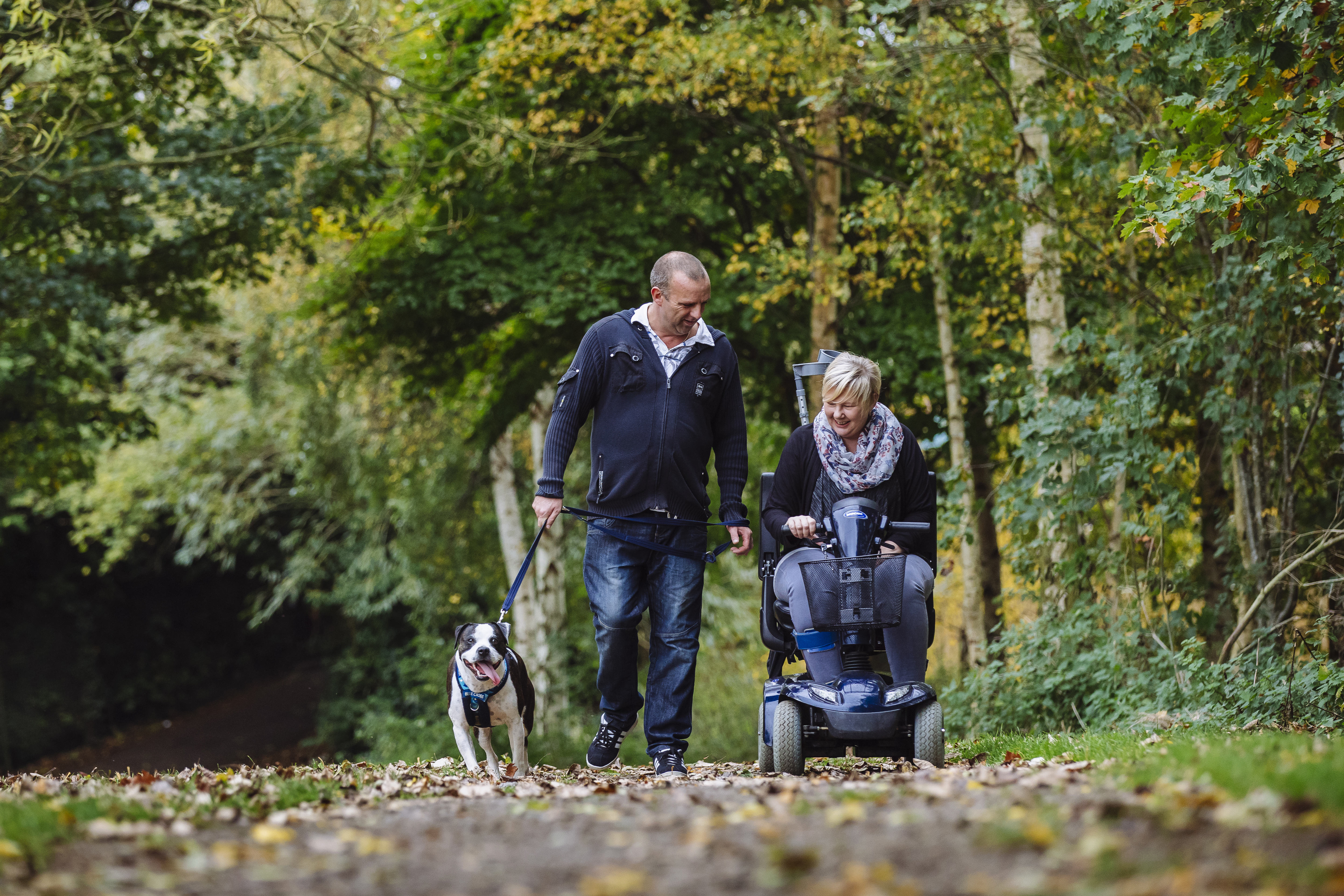 Hunter enjoys a walk with Jeff who is walking and Rachel who is in her mobility scooter