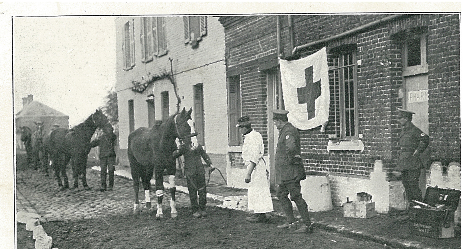 A blue cross flags hangs from a drainpipe outside a makeshift animal hospital in the First World War