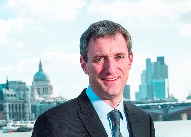 Photo of Chris Burghes looking towards the camera with St Paul's cathedral and the City of London skyline in the background