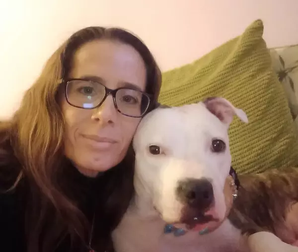 A women and a dog sitting closely together, cuddling.