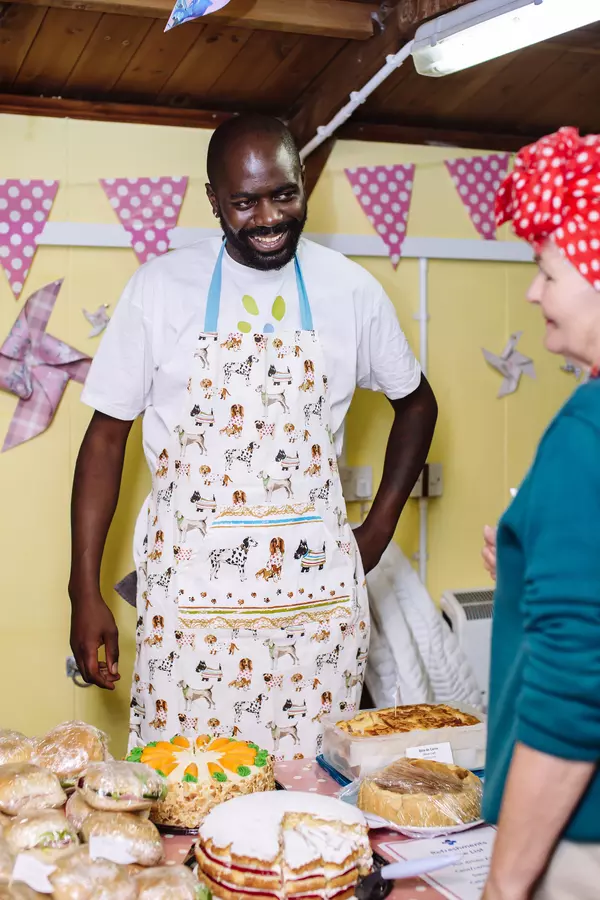 A fundraising volunteer sells cakes at a dog show.