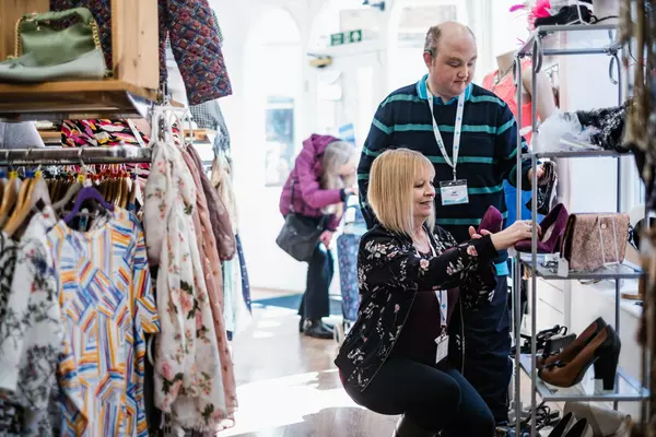 A woman and a man arrange a shelving display of shoes at our Hereford  charity shop