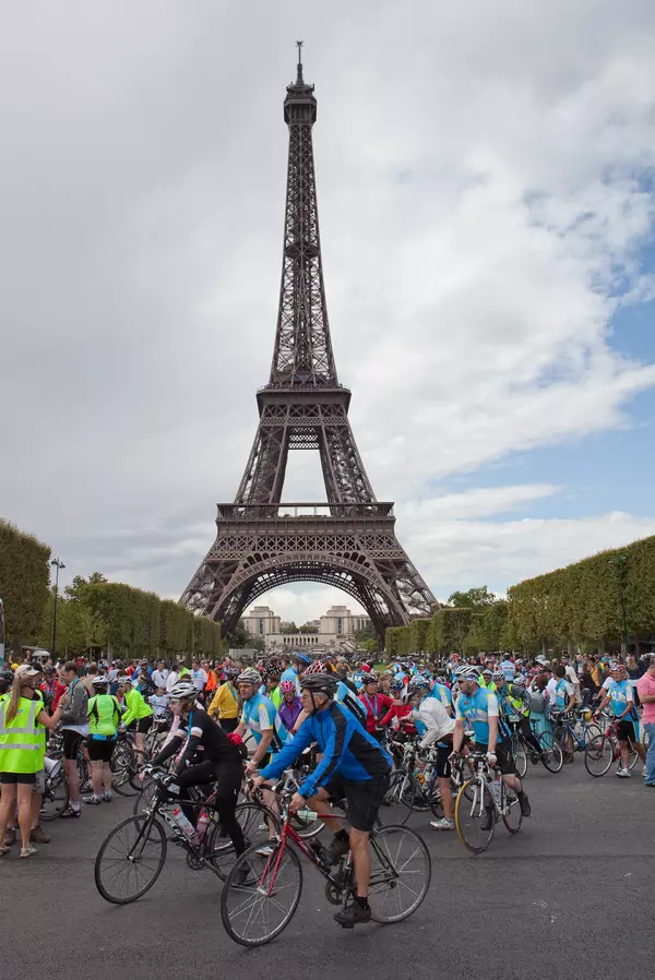 A group of cyclists participate in the London to Paris cycling challenge. The Eiffel Tower can be seen in the background.