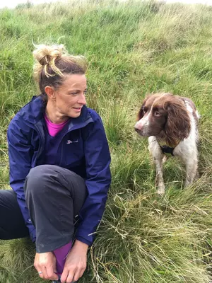 Liver and white springer spaniel Bailey stands in the grass next to owner Michelle as they look into each other's eyes