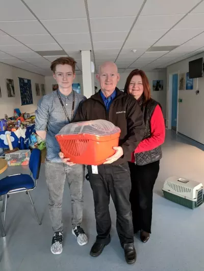 Three people stood with cage in arms