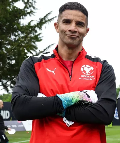 Former professional football goalkeeper David James standing in football gear in a field, posing for the camera.