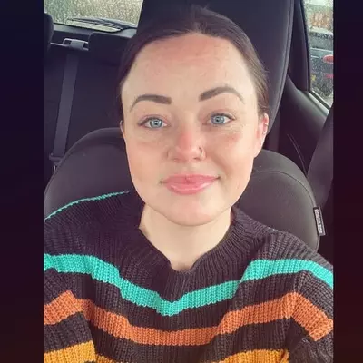 Fundraising team member Becky Smith takes a selfie in her car. She is smiling at the camera and wearing a striped jumper.