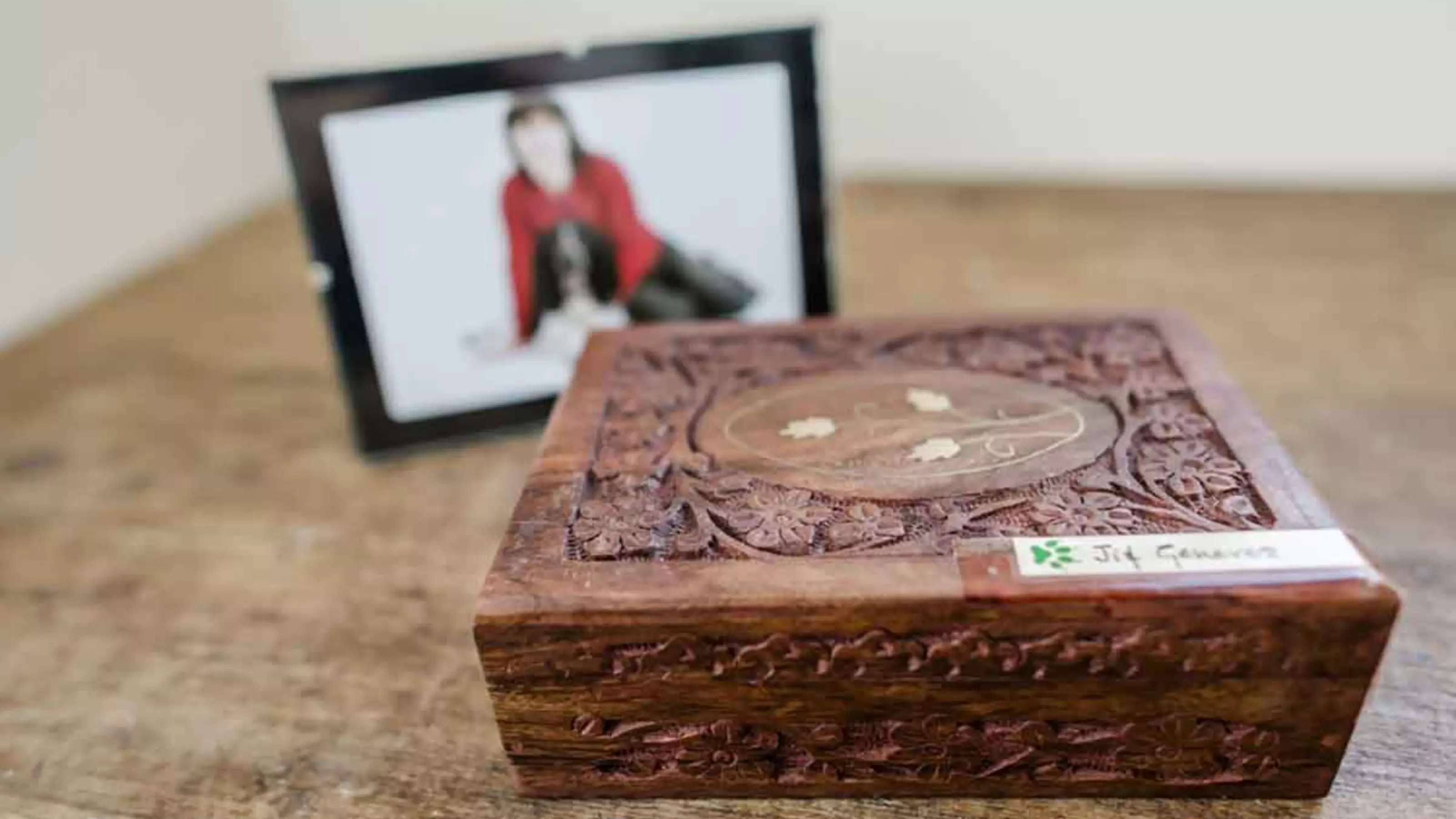 Box containing pet ashes with photo of pet and owner blurred in background