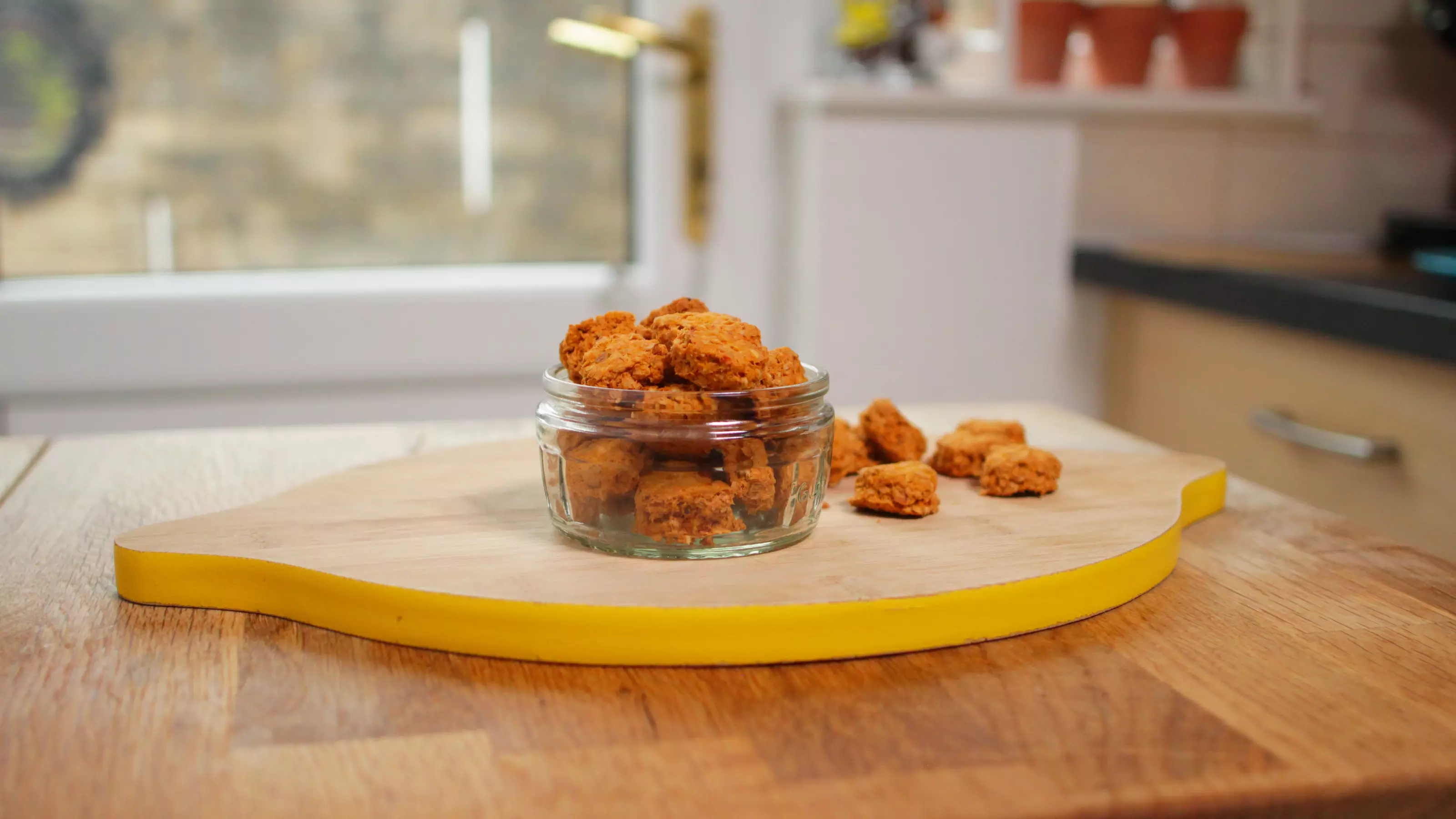 Bite-sized biscuits in a glass ramekin on a chopping board 