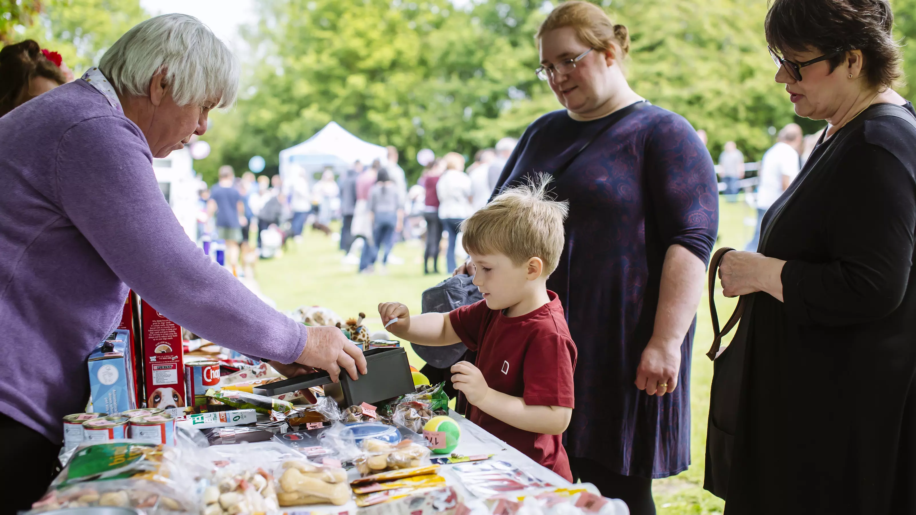 Young boy at fundraising stall putting money into the tin