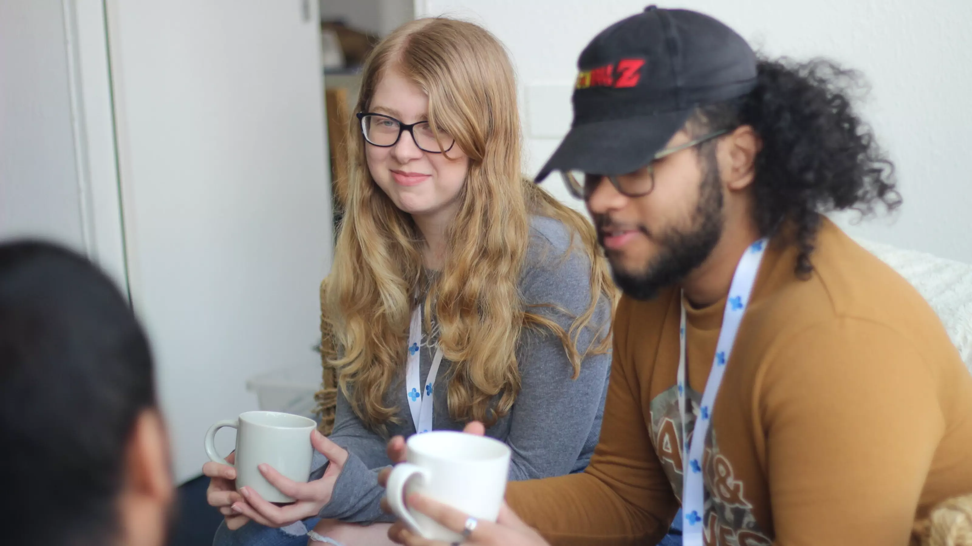 A young woman and young man sitting next to each other chatting over a cup of tea