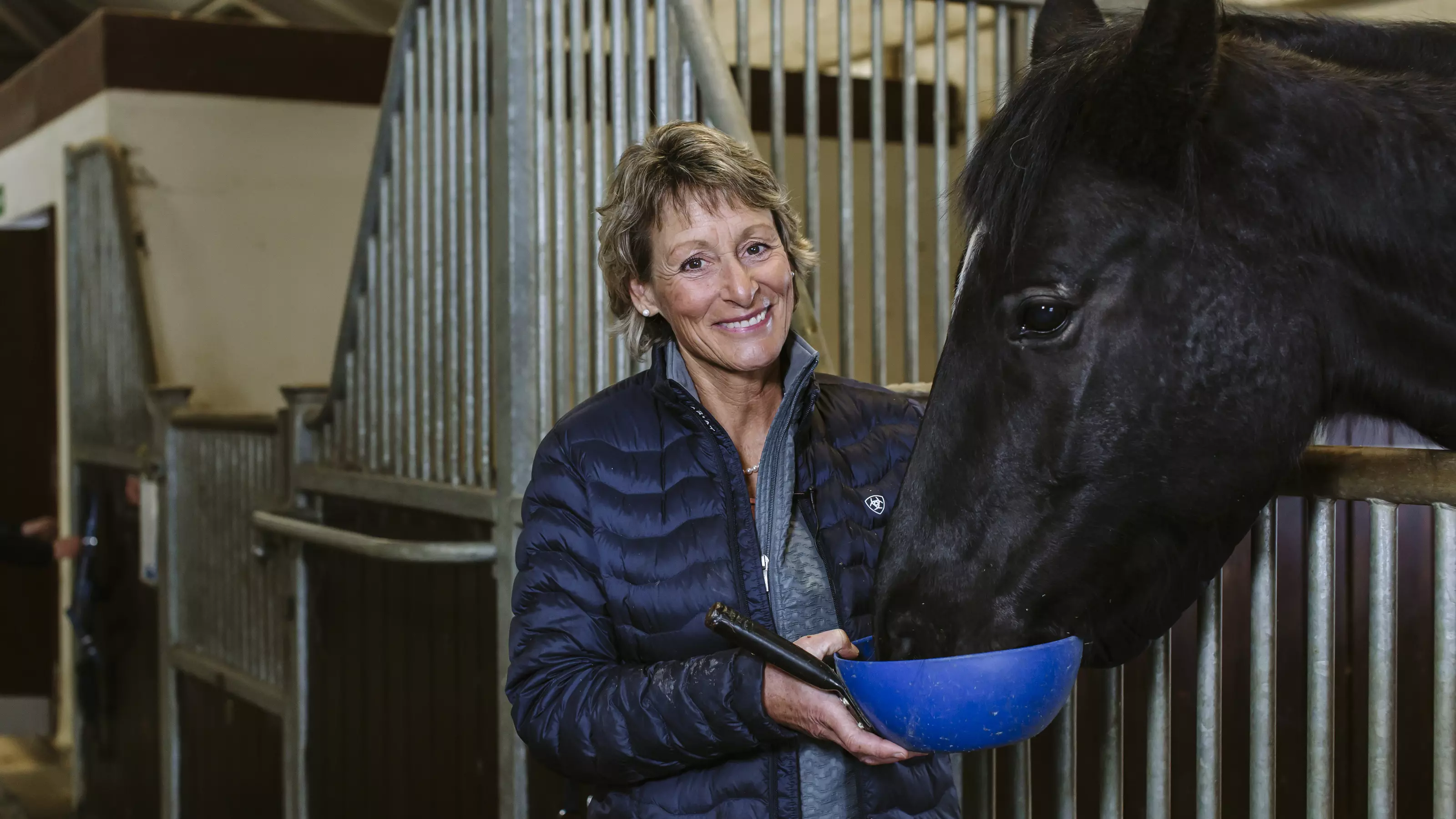 Mary King feeds a horse from a feeding bowl.