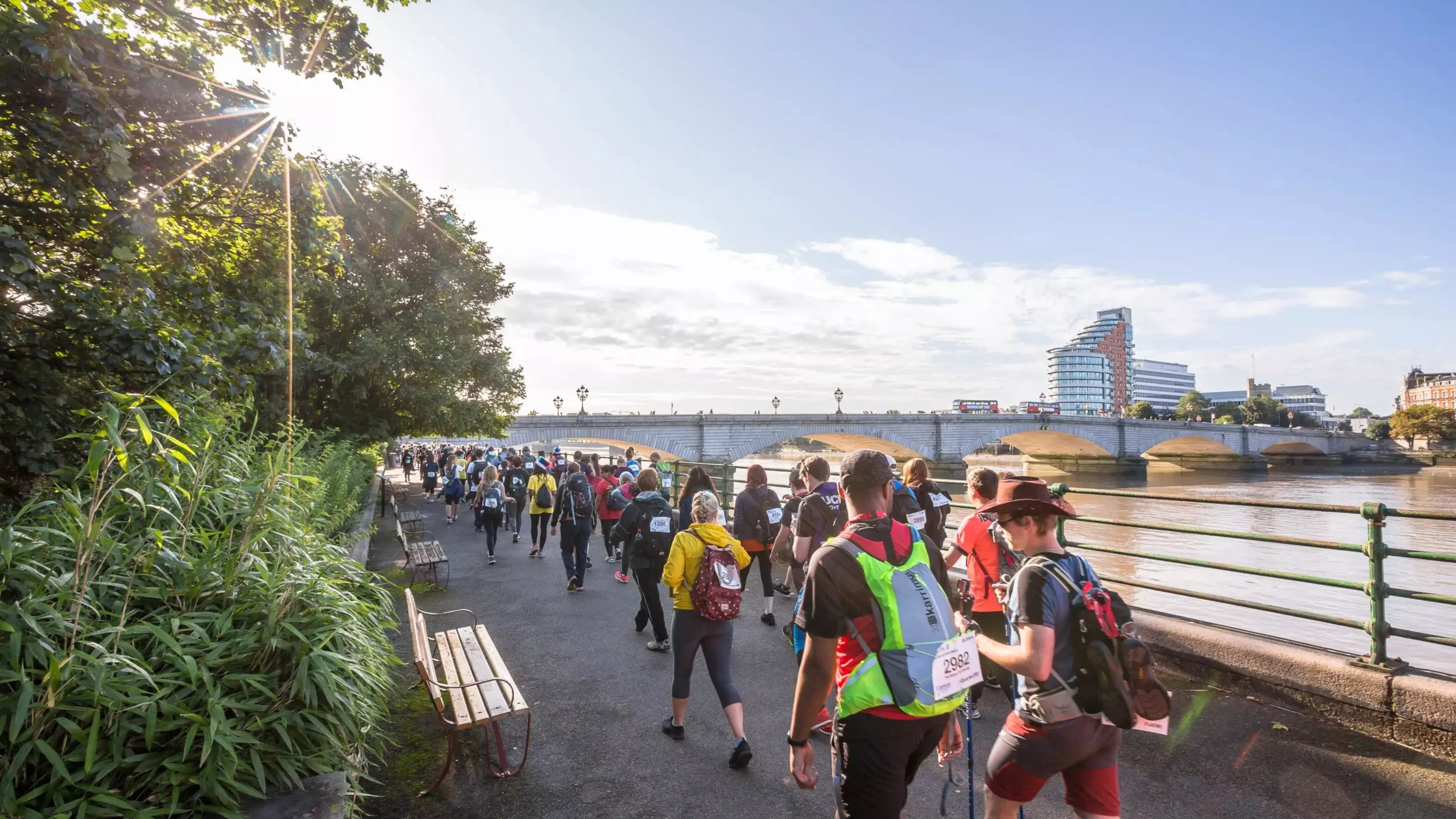 Attendees of the Thames Bridge Trek walk by the Thames river.
