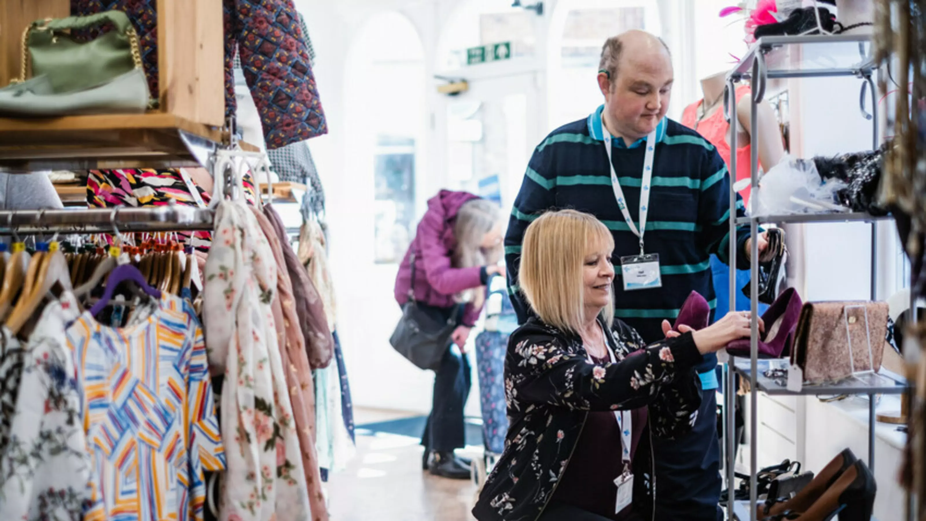 A woman and a man arrange a shelving display of shoes at our Hereford charity shop