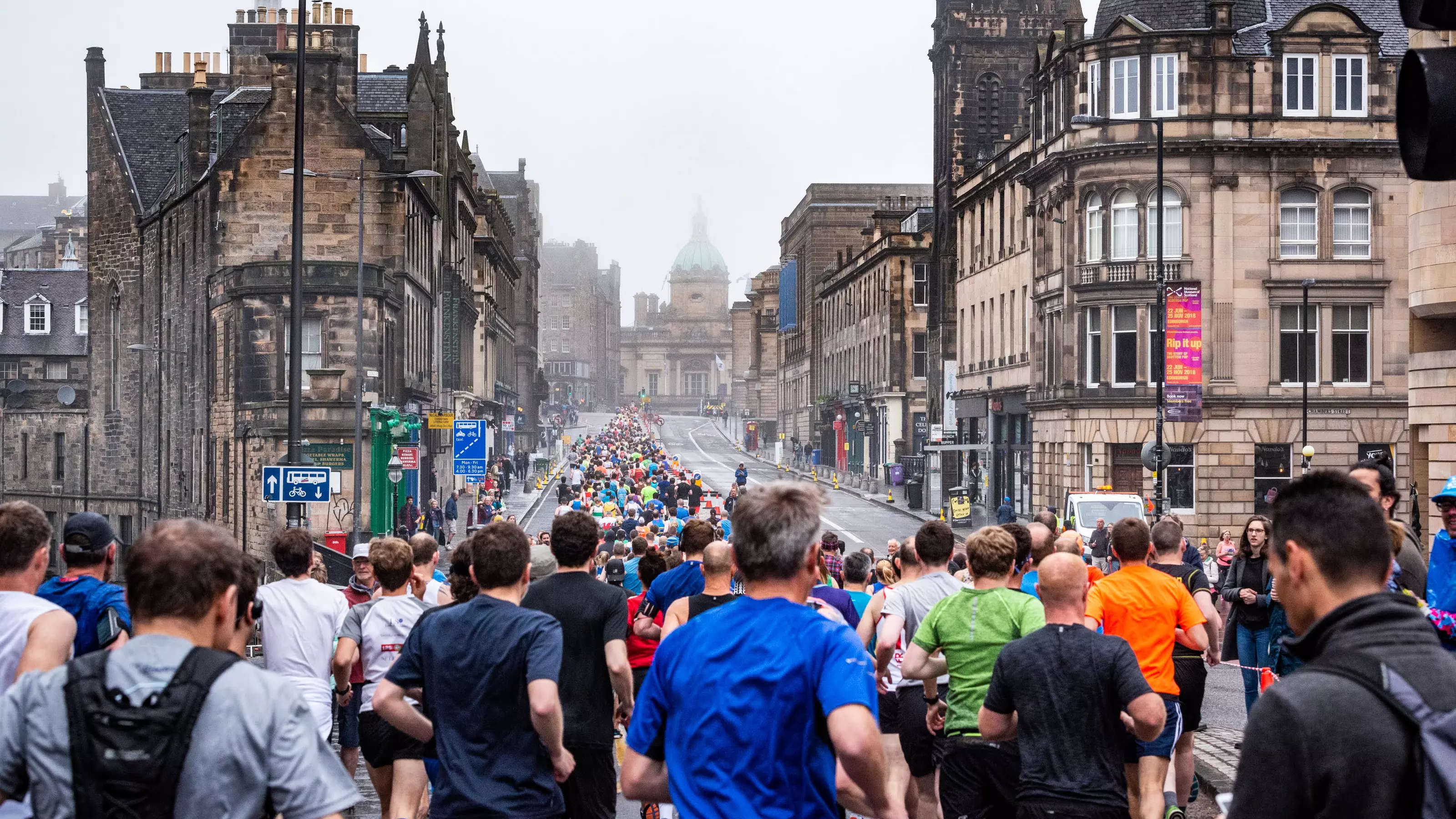 A large group of people running through Edinburgh as part of the Edinburgh Half Marathon