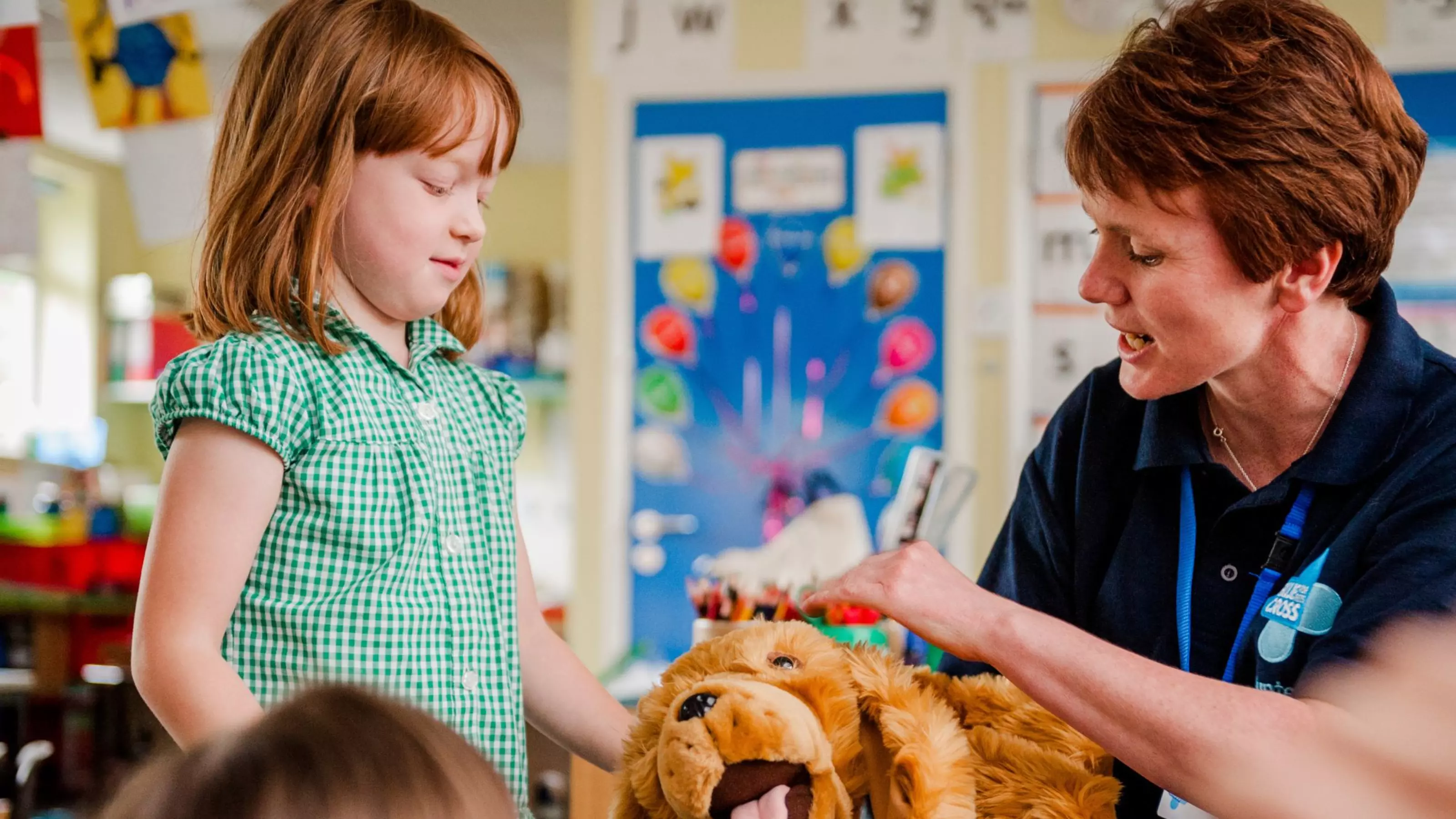 A volunteer education speaker shows a child how to pet a dog.