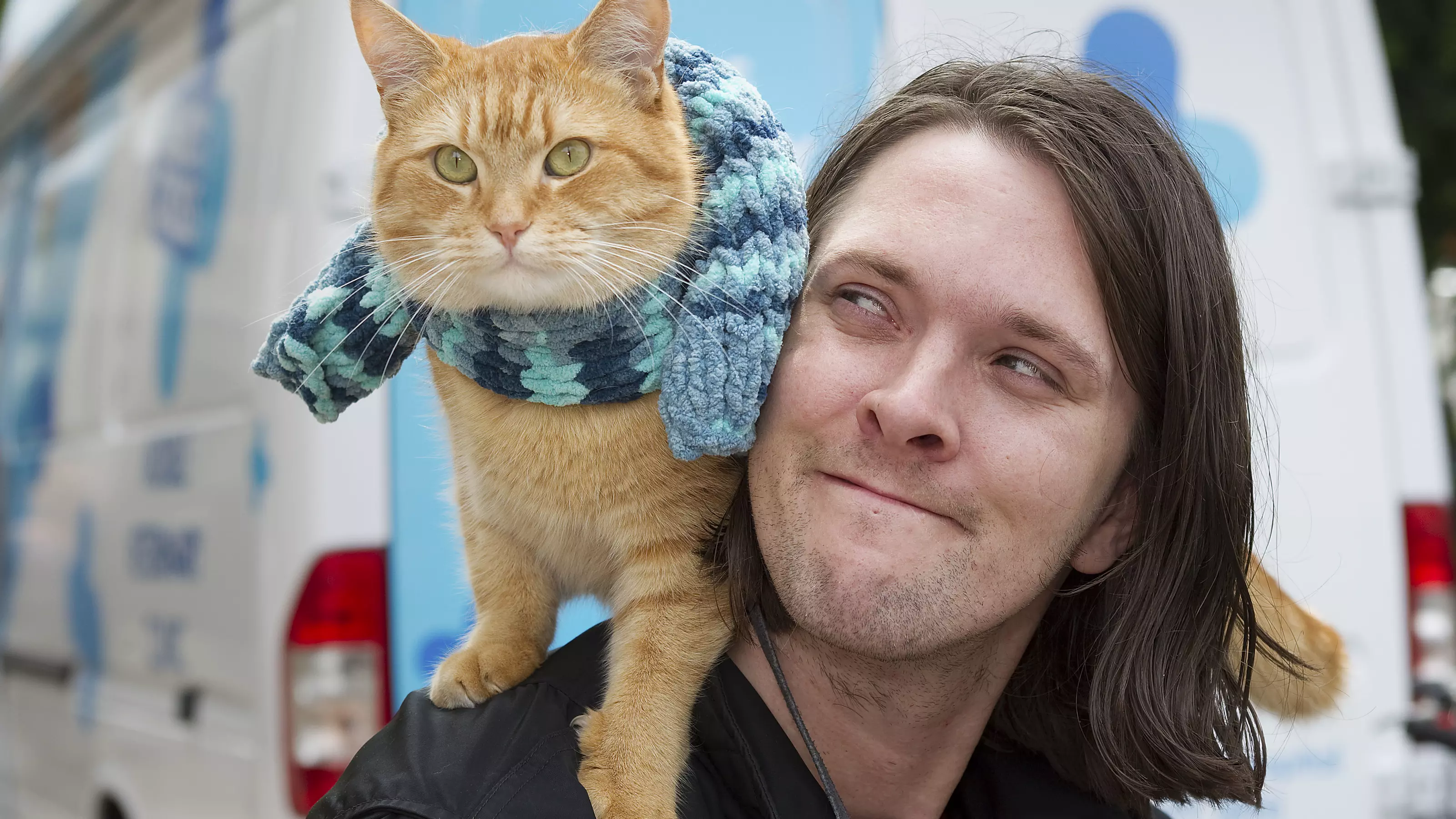 Street cat Bob sits on James Bowen's shoulder by the Blue Cross mobile clinic which helped them through tough times