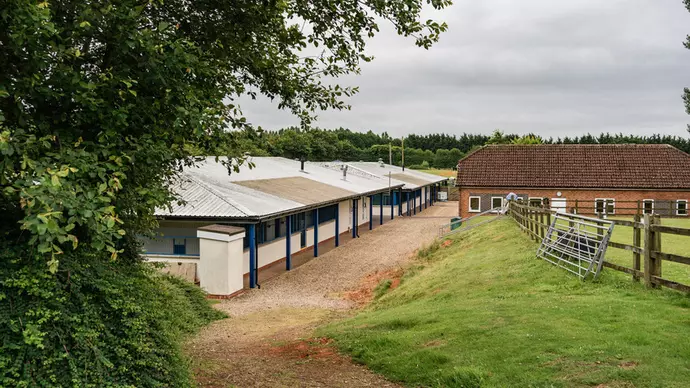 A single story building with blue pillars and a grassy space to the right