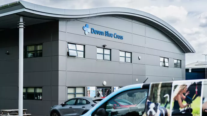 A grey building with Blue Cross branding and cars outside