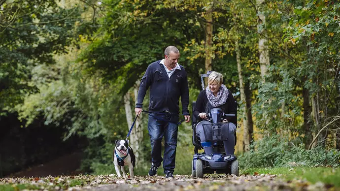 Hunter enjoys a walk with Jeff who is walking and Rachel who is in her mobility scooter