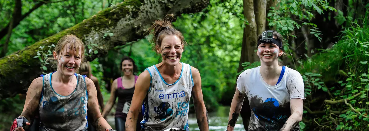 Three women running through river
