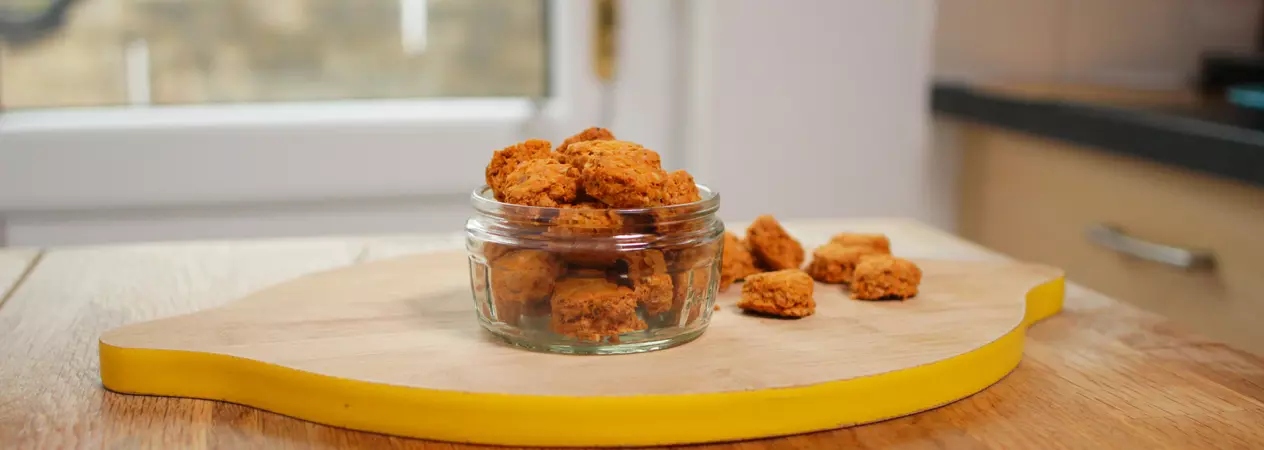 Bite-sized biscuits in a glass ramekin on a chopping board 