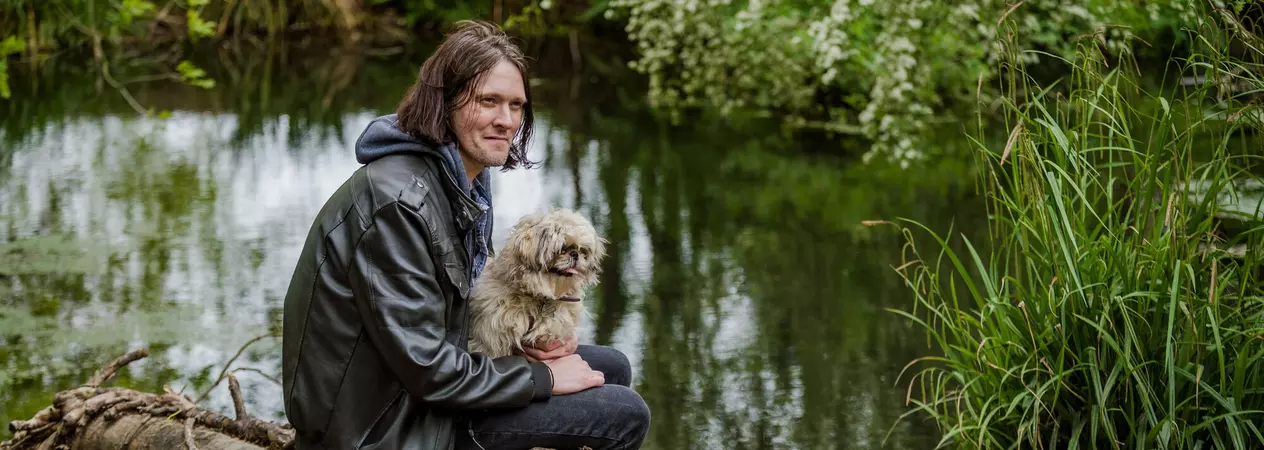 James and Chewbie sitting together on a log beside a river