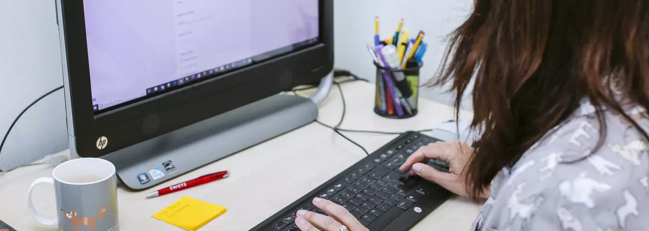 Woman typing on keyboard looking at computer screen