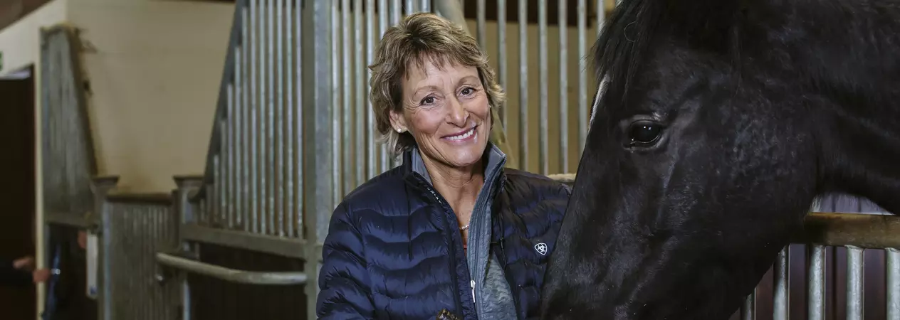 Mary King feeds a horse from a feeding bowl.
