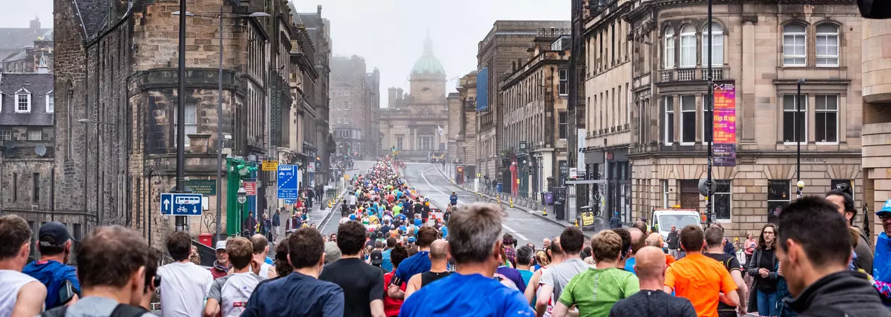 A large group of people running through Edinburgh as part of the Edinburgh Half Marathon